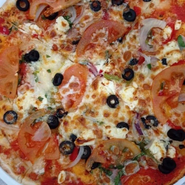 Una pizza con tomates y aceitunas encima.