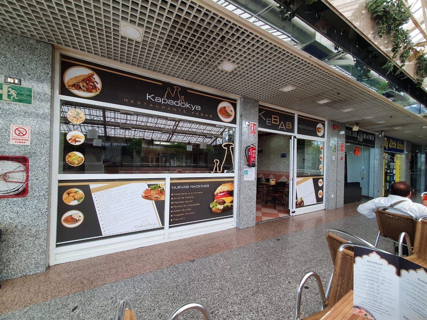Un hombre está sentado en una mesa frente a un restaurante.