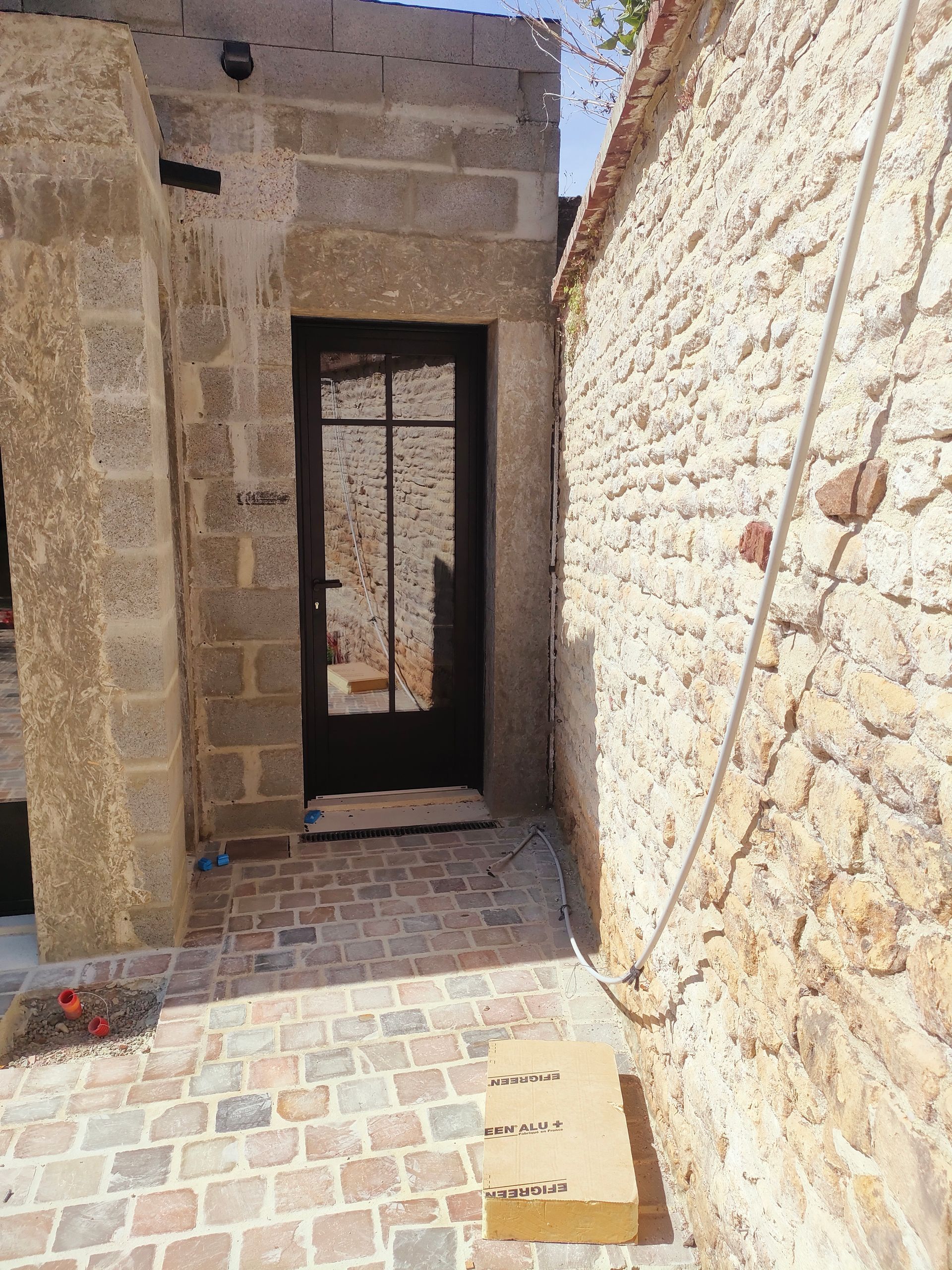 Entrée en pierre apparente et porte d'entrée de couleur noire
