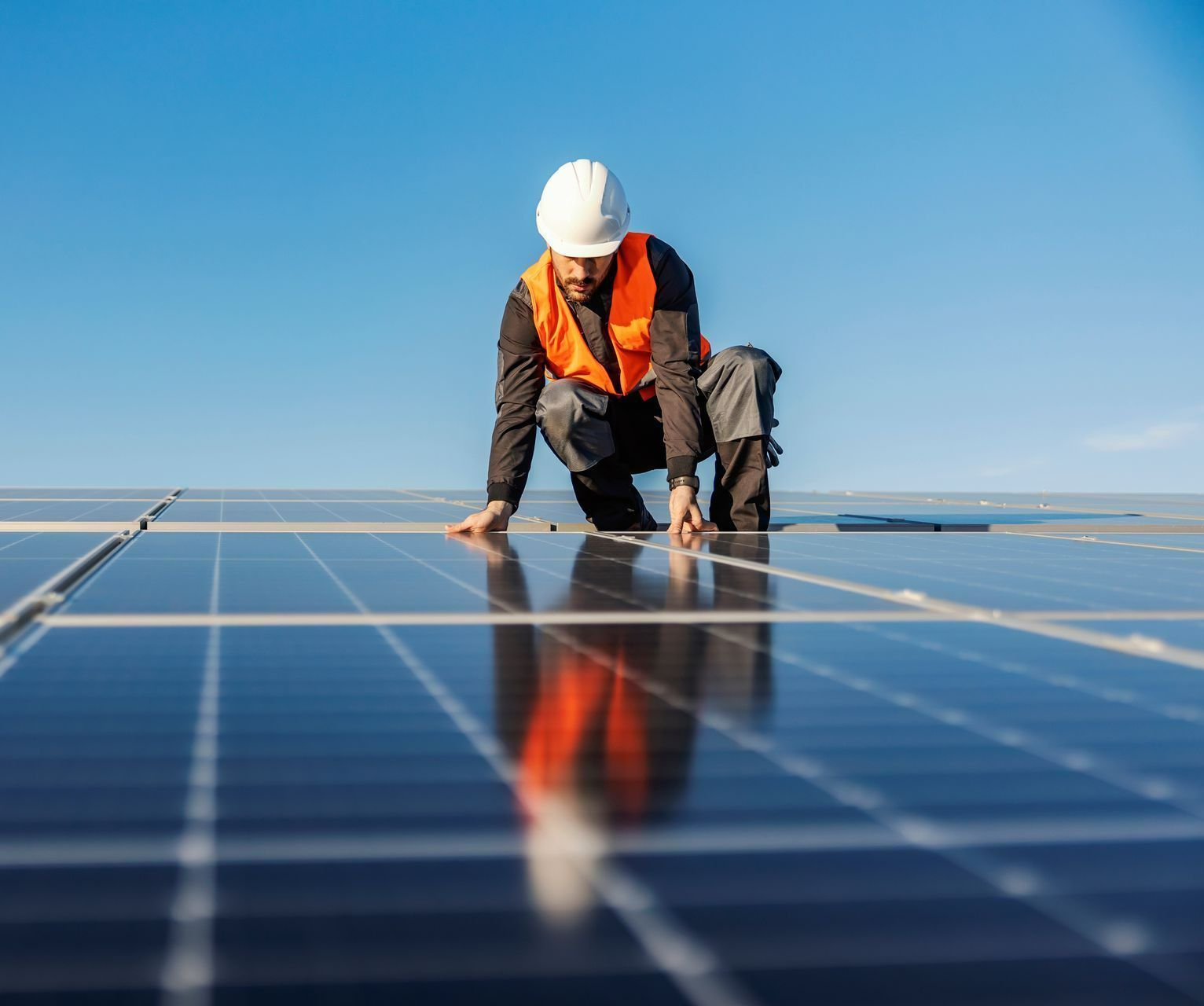 Un homme sur un toit installe des panneaux solaires