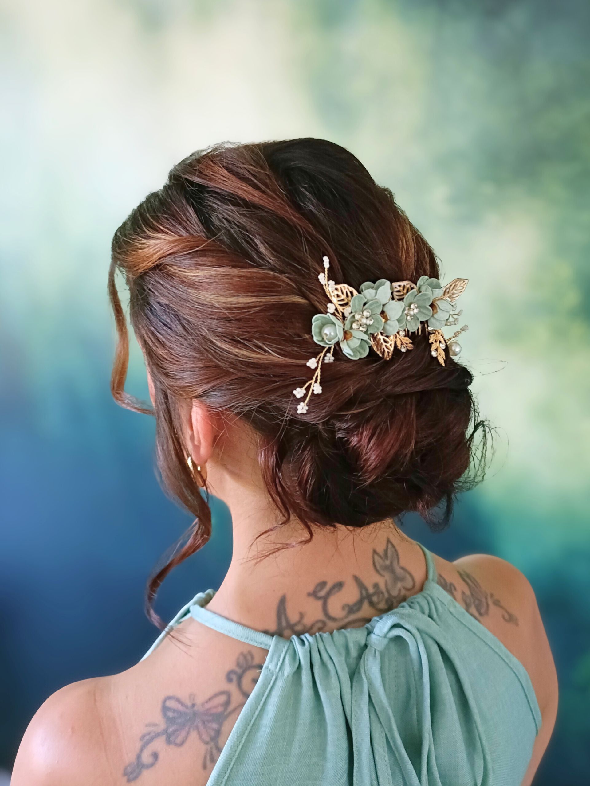 Femme avec une coiffure relevée et un postiche fleuri, portant une robe verte.