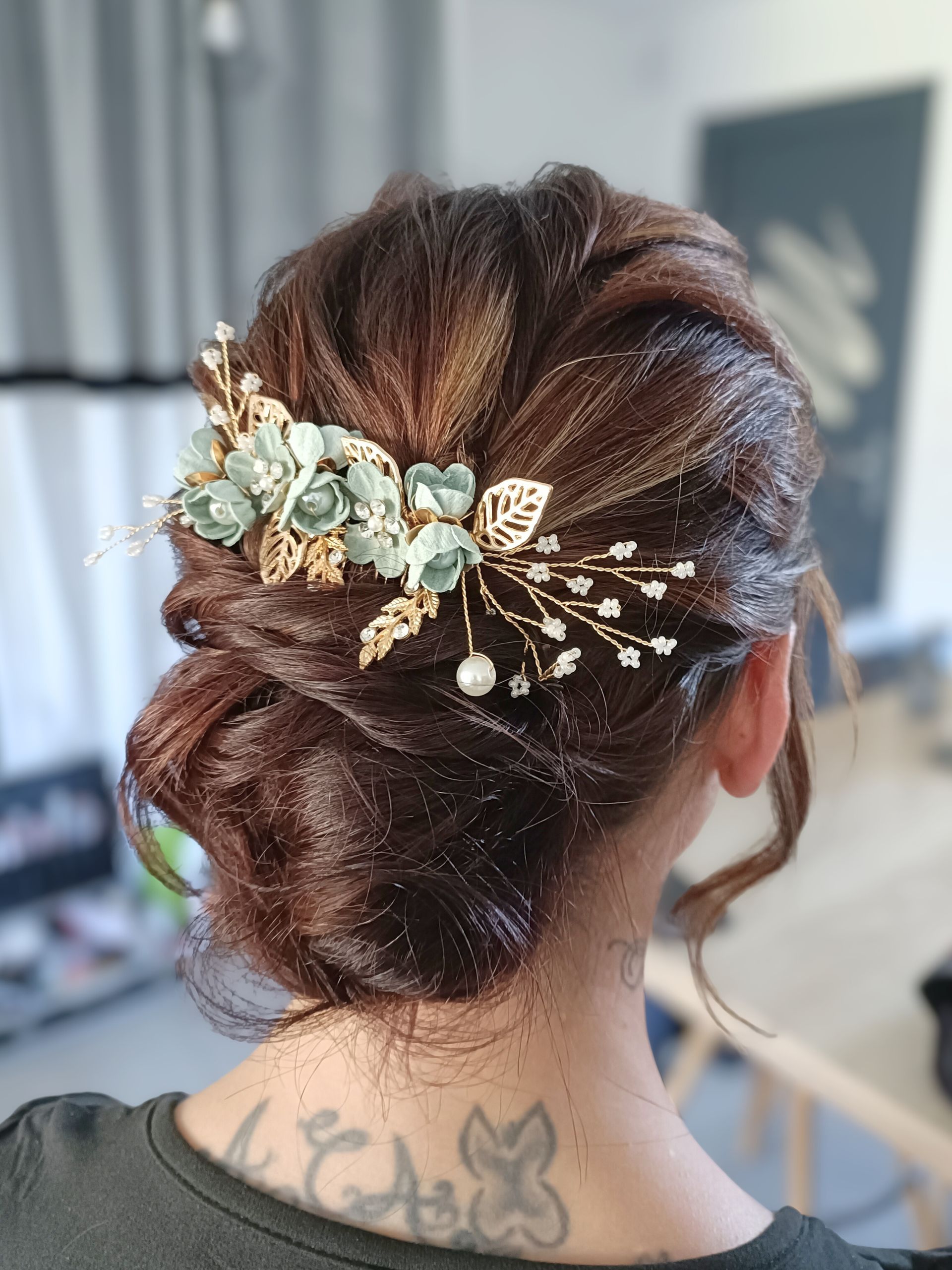 Femme avec une coiffure de chignon marron ornée d'un postiche floral doré et bleu sarcelle.
