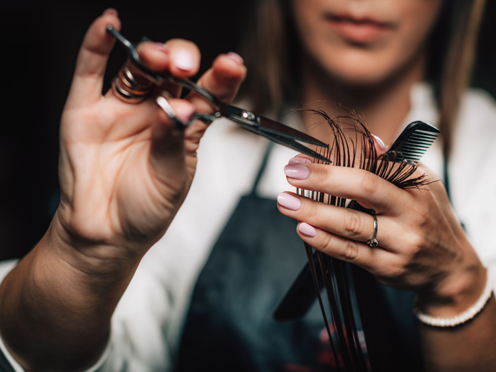 Coiffeur coupant des mèches de cheveux avec des ciseaux et un peigne.