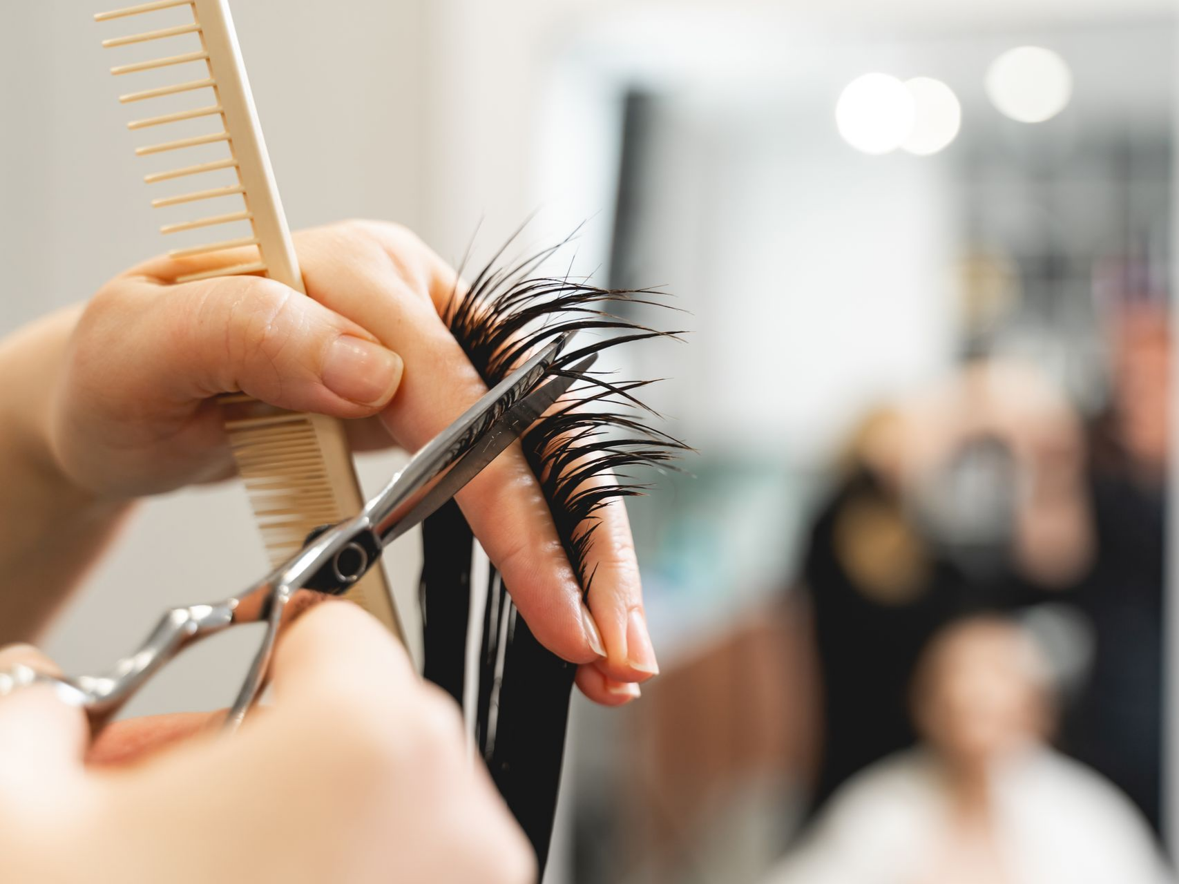 Coiffeur coupant les cheveux avec des ciseaux et un peigne dans un salon.