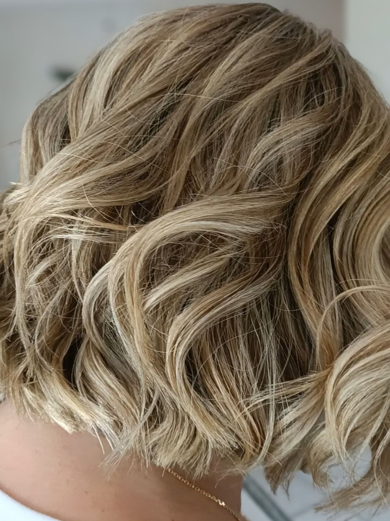 Cheveux blonds ondulés avec des mèches.
