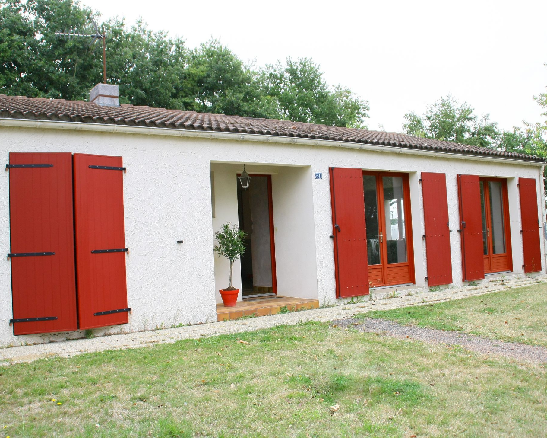 Maison de plain-pied avec des volets battants rouges