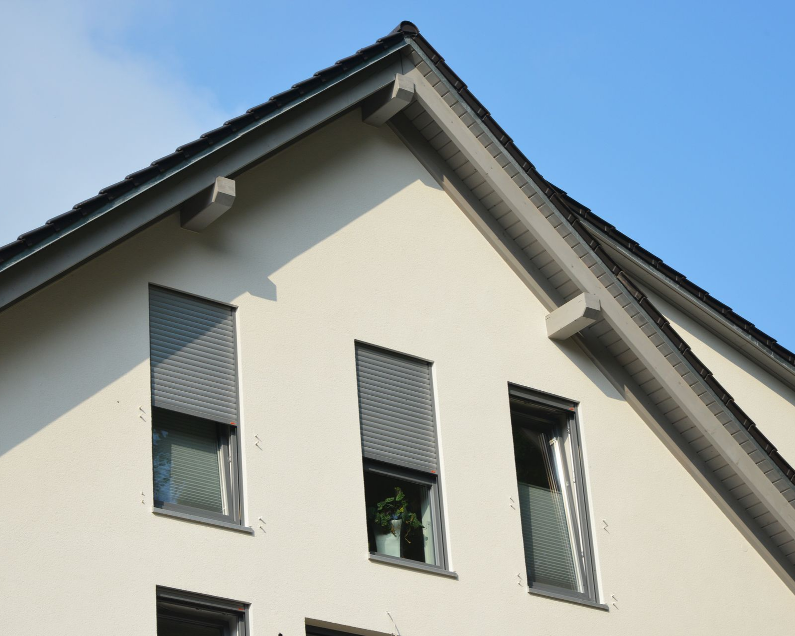 Pignon d'une maison avec trois fenêtres avec volets  à demi fermés