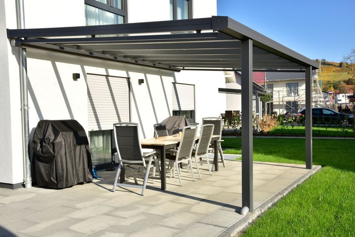 Pergola moderne en alu sur une terrasse avec un salon de jardin