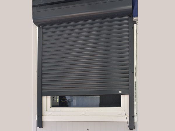 Volets roulants gris devant une fenêtres
