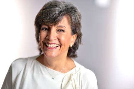 Frau mit kurzem grauen Haar, lächelnd, trägt eine weisse Bluse, vor einem verschwommenen weissen Hintergrund.