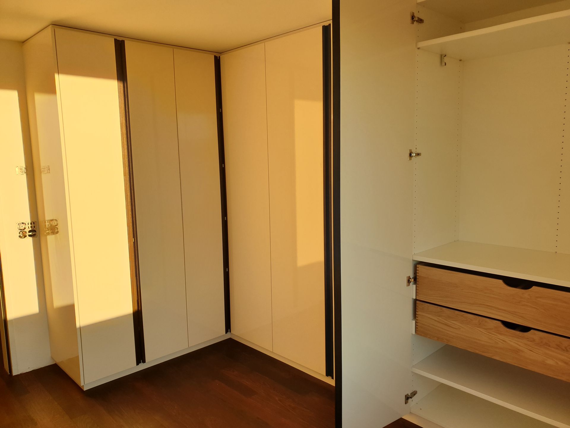 Silberner Industrie-Scheinwerfer auf einem grünen Holzständer, vor einer Backsteinmauer und einem Garagentor.