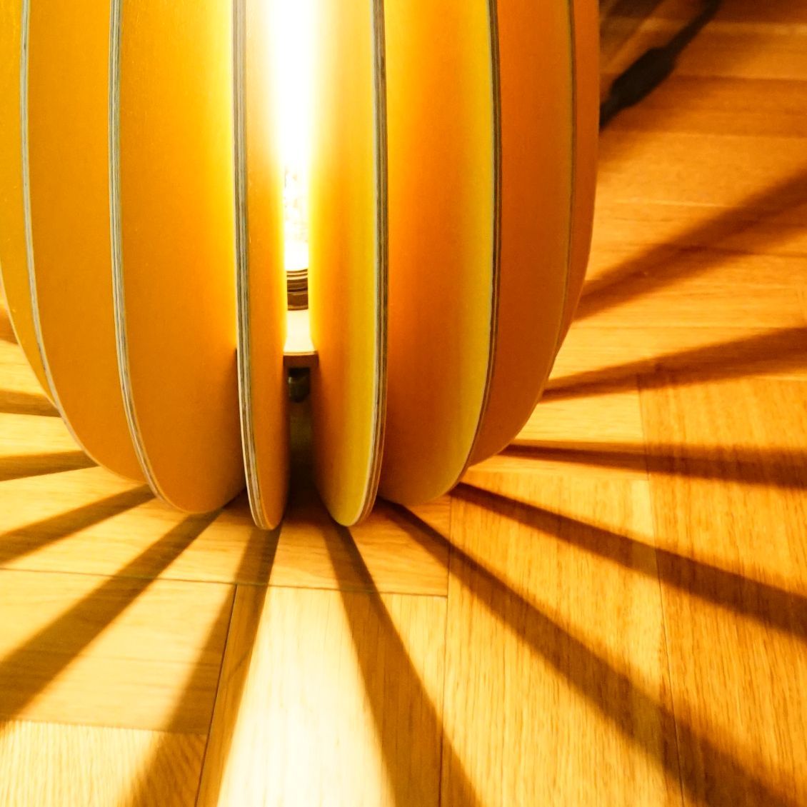 Eine blaue Kugelpendelleuchte hängt über einem grauen Sofa mit bunten Kissen und einer Pflanze. Dunkelviolette Wände.