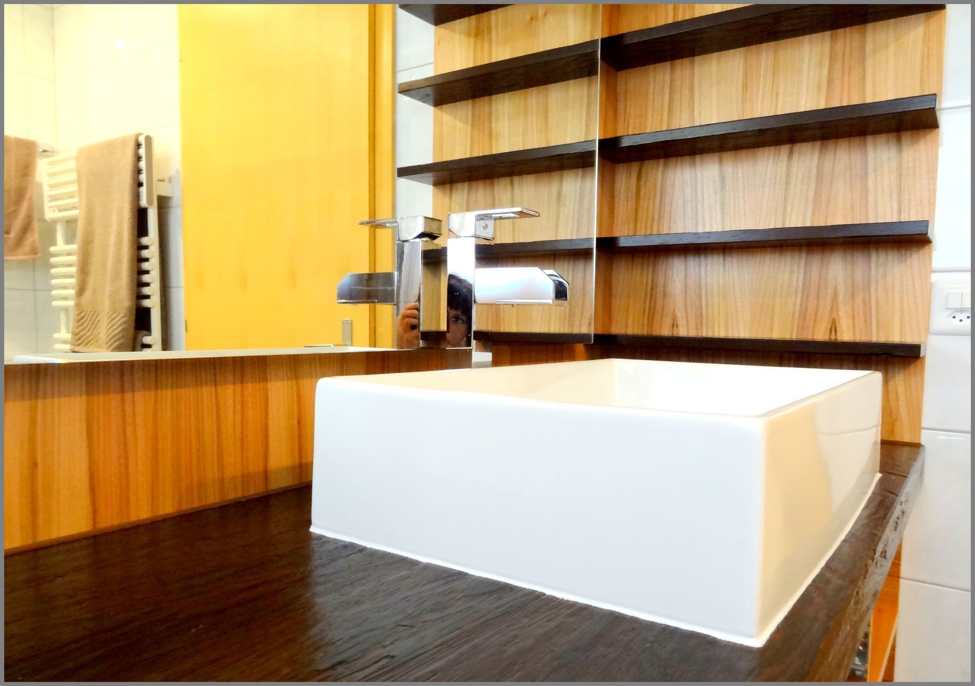 Eine kugelförmige Holzlampe steht auf dem Boden und erhellt einen dunklen Raum, in dem auf einem Konsolentisch eine Pflanze steht.