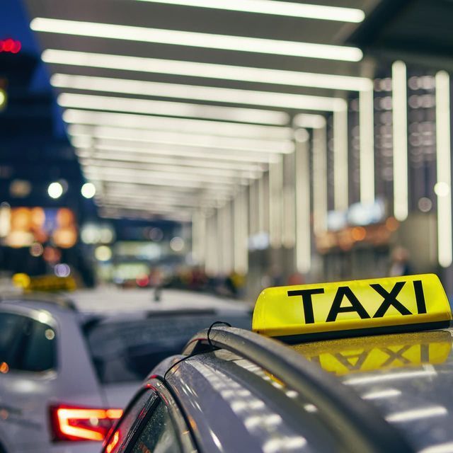 Panneau jaune de taxi sur le toit d'une voiture, garée à une station de taxis, illuminé la nuit.