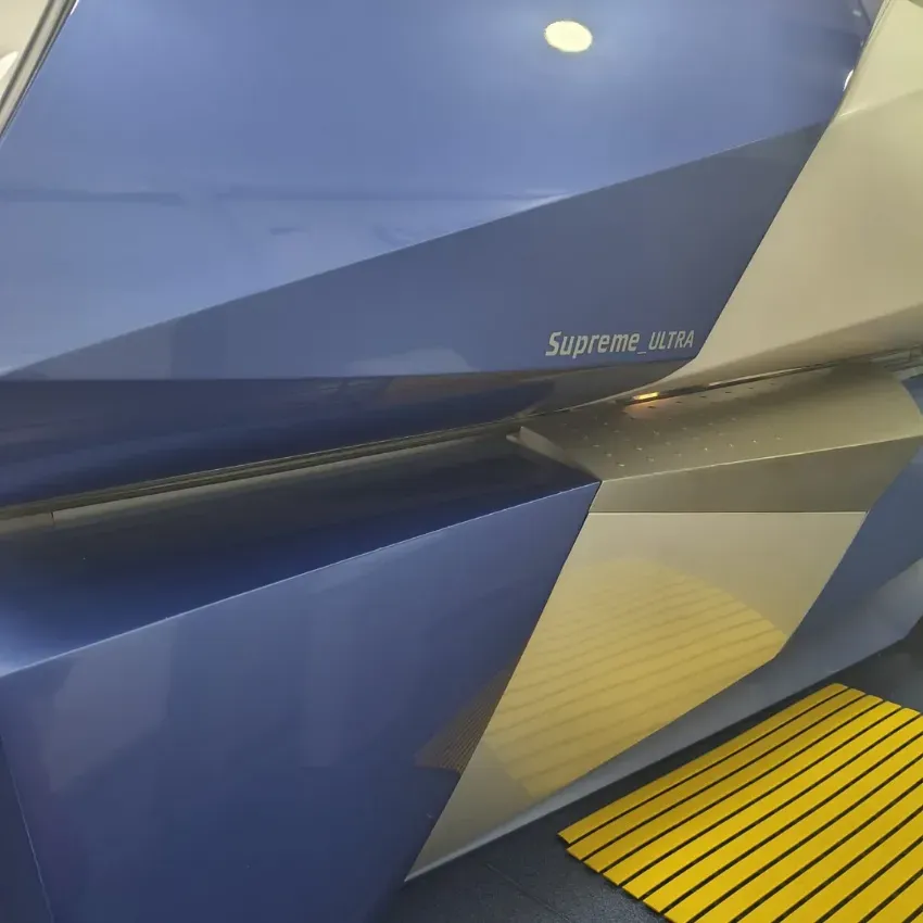 Tren azul y plateado con borde de andén a rayas amarillas que refleja las luces superiores
