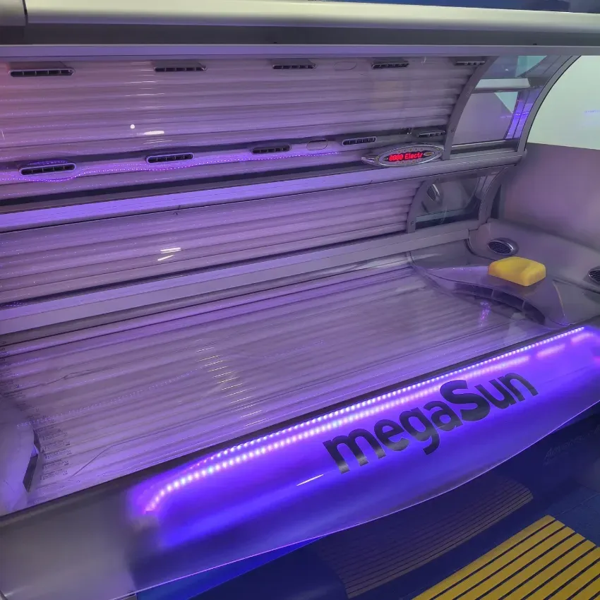 Cama de bronceado con iluminación violeta, cubierta transparente y el logotipo “megaSun”.