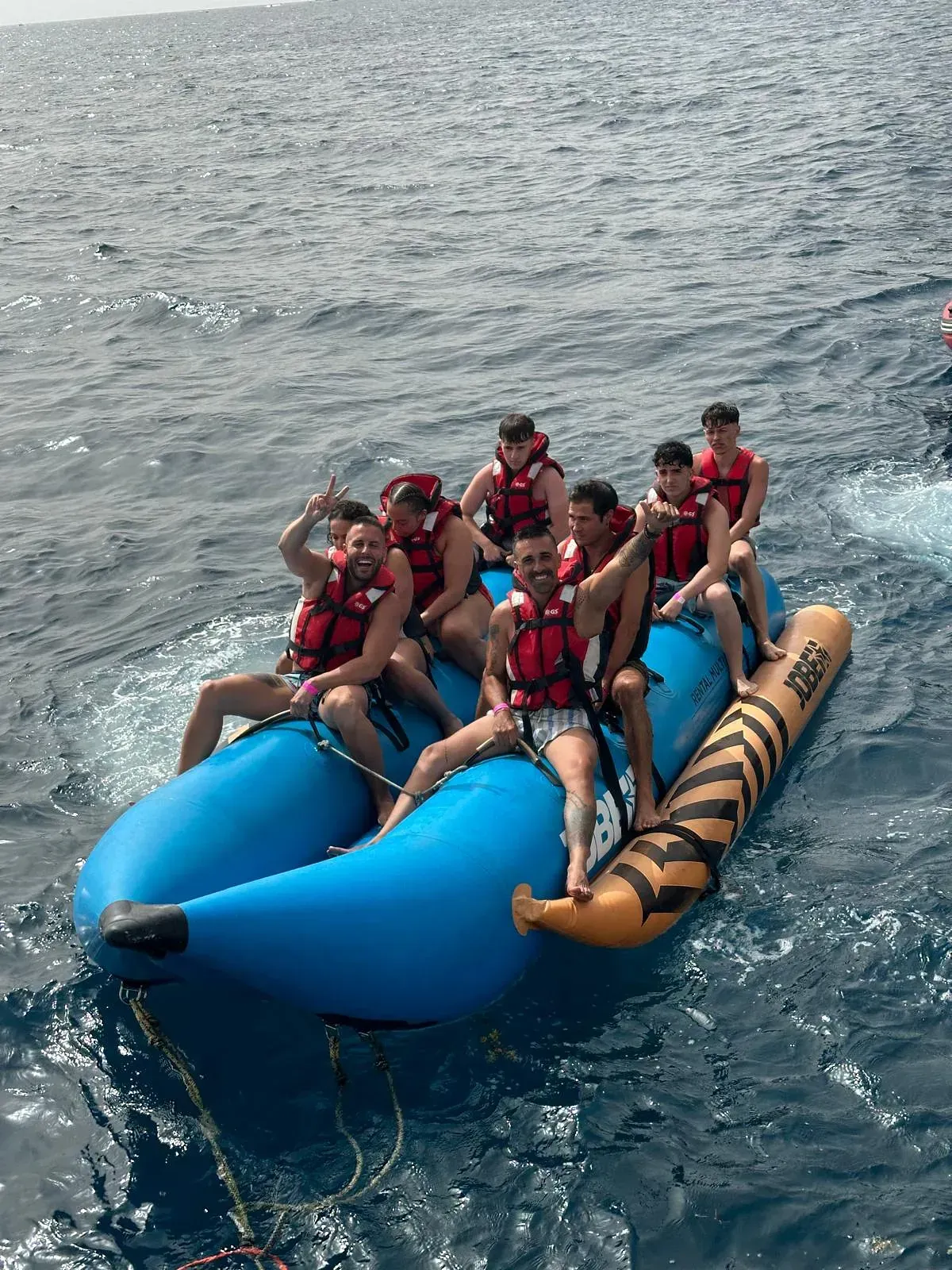 Un grupo de personas viajan en un bote banana en el océano.