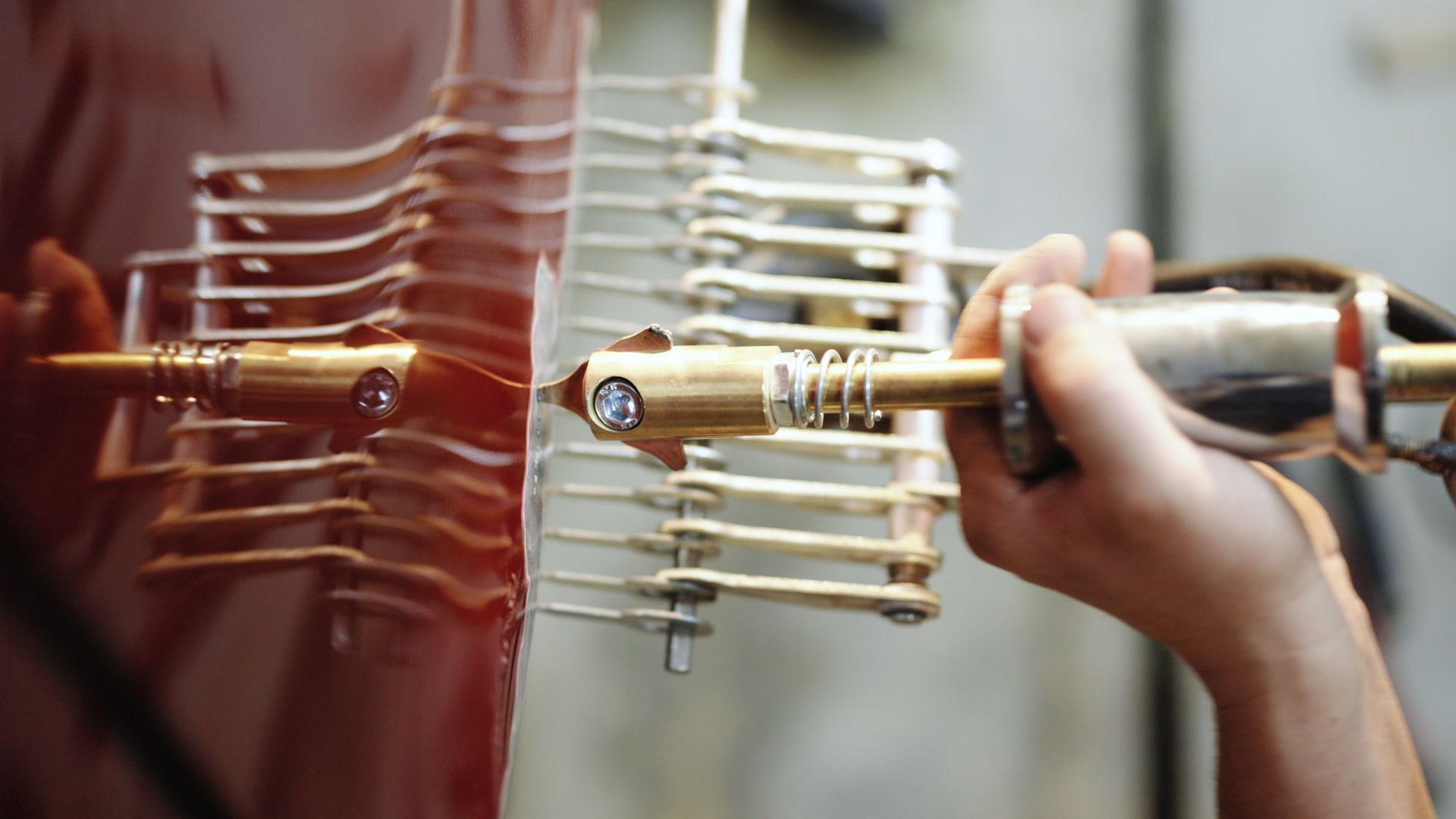 Eine Person benutzt in einer Reparaturwerkstatt ein Ausbeulwerkzeug an einem roten Karosserieteil.