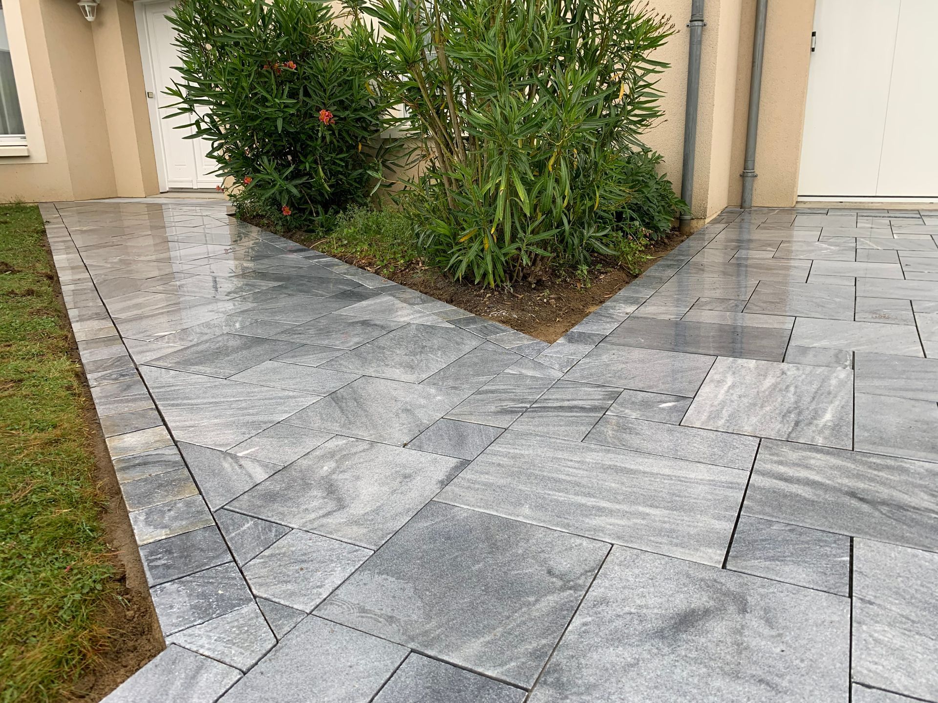 Allée extérieure dallée menant à un garage et une porte d'entrée