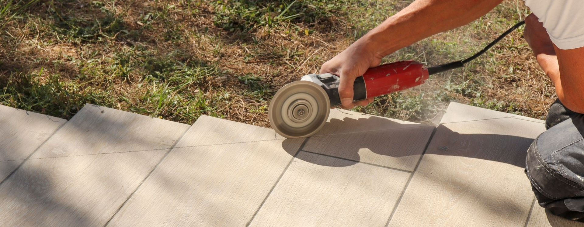 Gros plan sur un professionnel qui coupe du carrelage en extérieur