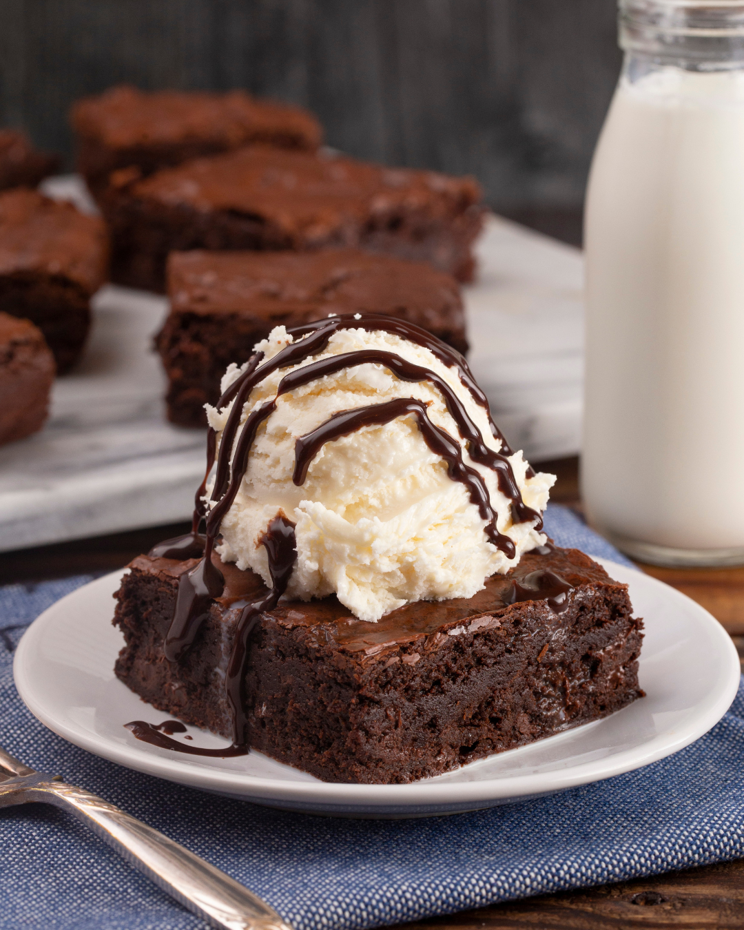 Un brownie con helado y salsa de chocolate en un plato.