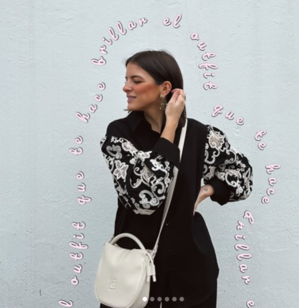 Una mujer que lleva un suéter blanco y negro y un bolso blanco.