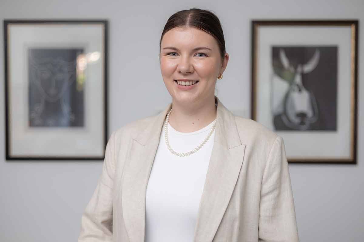 Eine Frau steht vor einer Wand mit Gemälden.