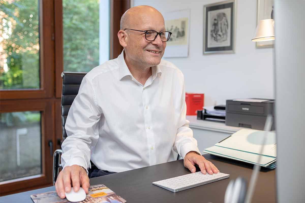 Ein Mann sitzt an einem Schreibtisch vor einem Computer.