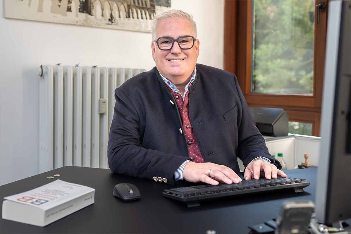 Ein Mann sitzt an einem Schreibtisch und tippt auf einer Tastatur.