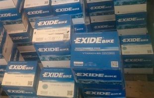 Una pila de cajas de baterías para bicicletas Exide, de color azul y blanco, apiladas unas junto a otras.