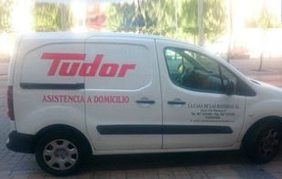 Una furgoneta de servicio Tudor blanca aparcada en una calle con texto rojo en el lateral que anunciaba