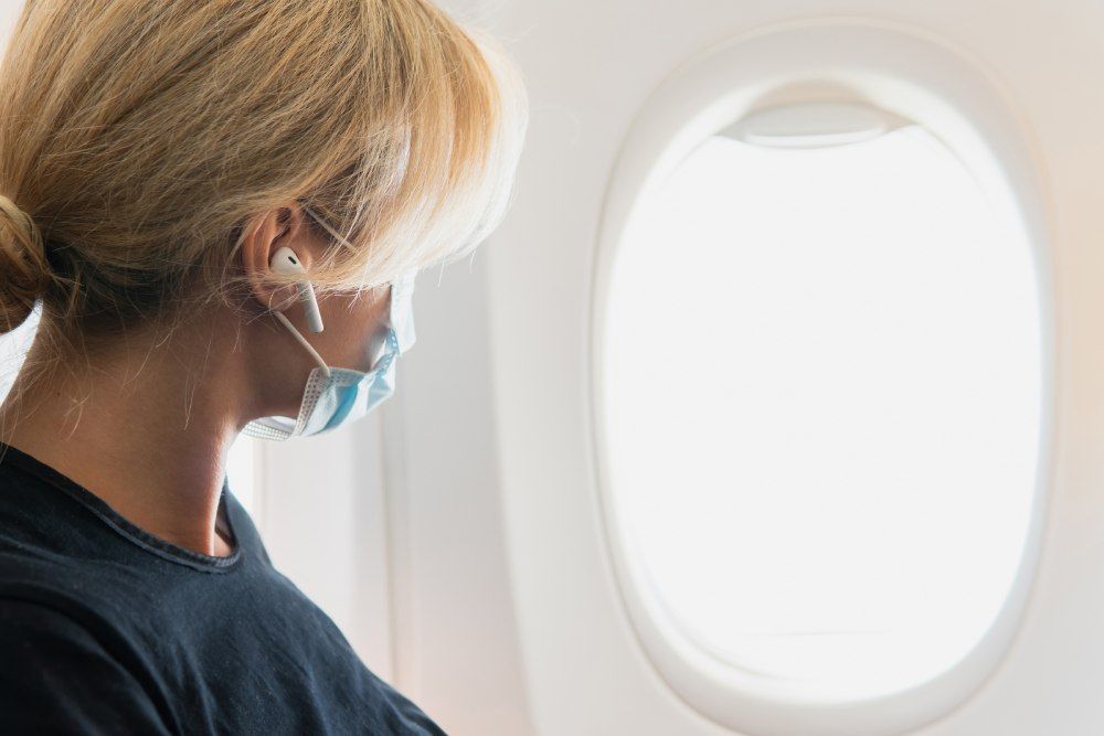 Femme avec masque sanitaire regardant par le hublot d'un avion