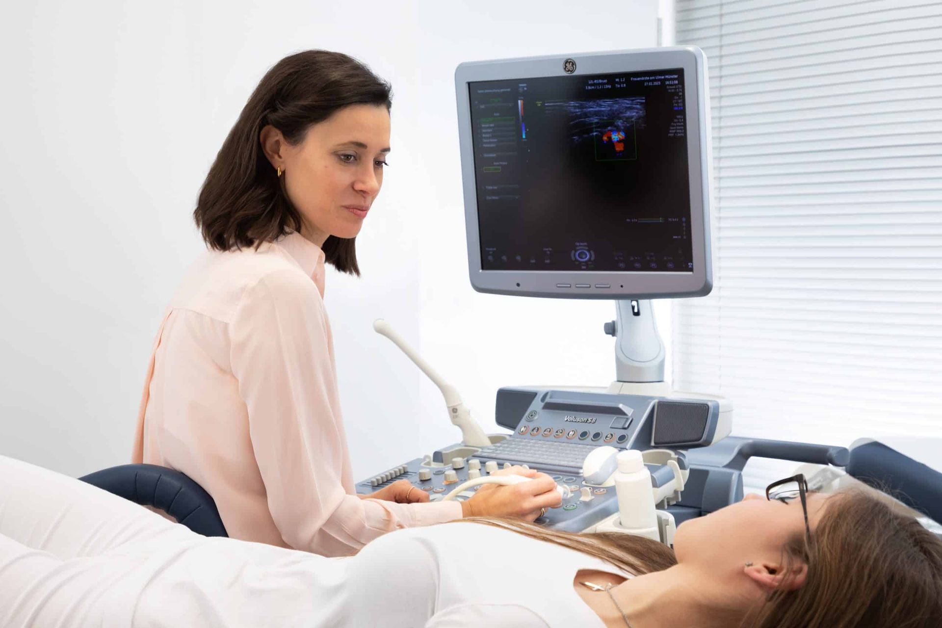 Ein Arzt führt in einer Klinik eine Ultraschalluntersuchung durch, während der Patient auf dem Untersuchungstisch liegt.