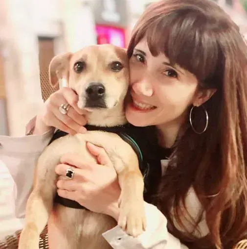 Una mujer sostiene un perro pequeño en sus brazos.