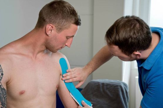 Therapeut bringt Stützband am Arm des Patienten an