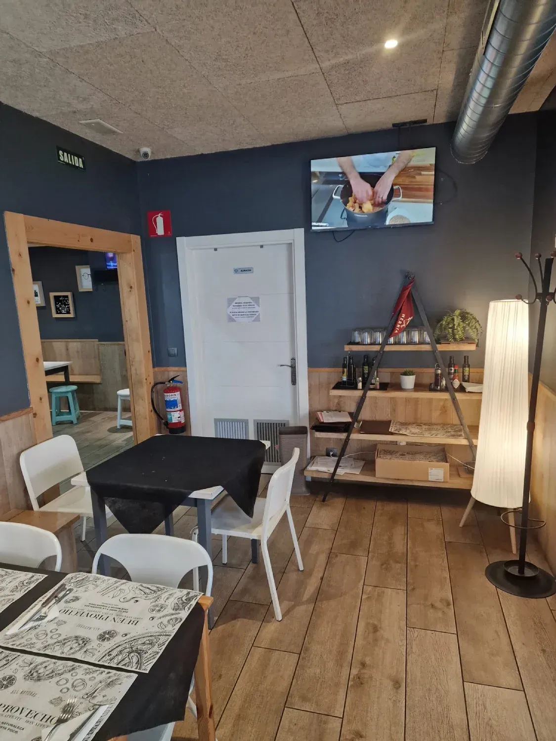 Un restaurante con mesas y sillas y un televisor en la pared.