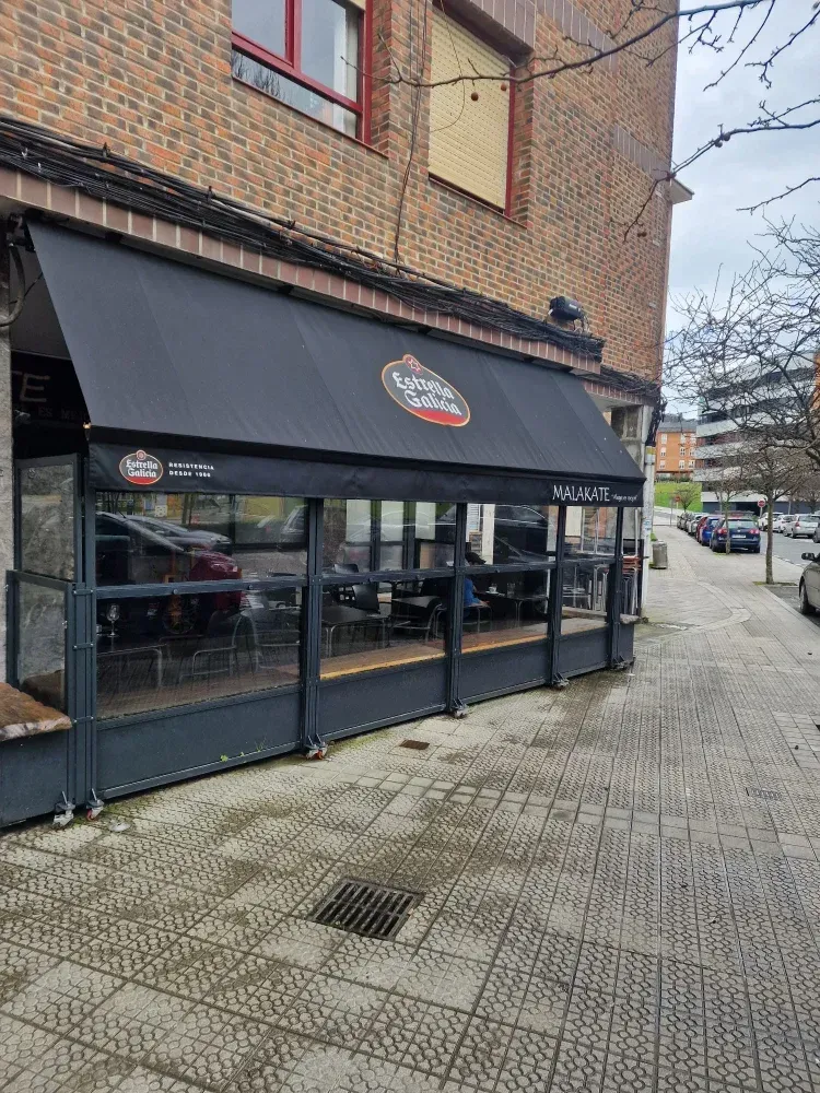 Un restaurante con un toldo negro al costado.