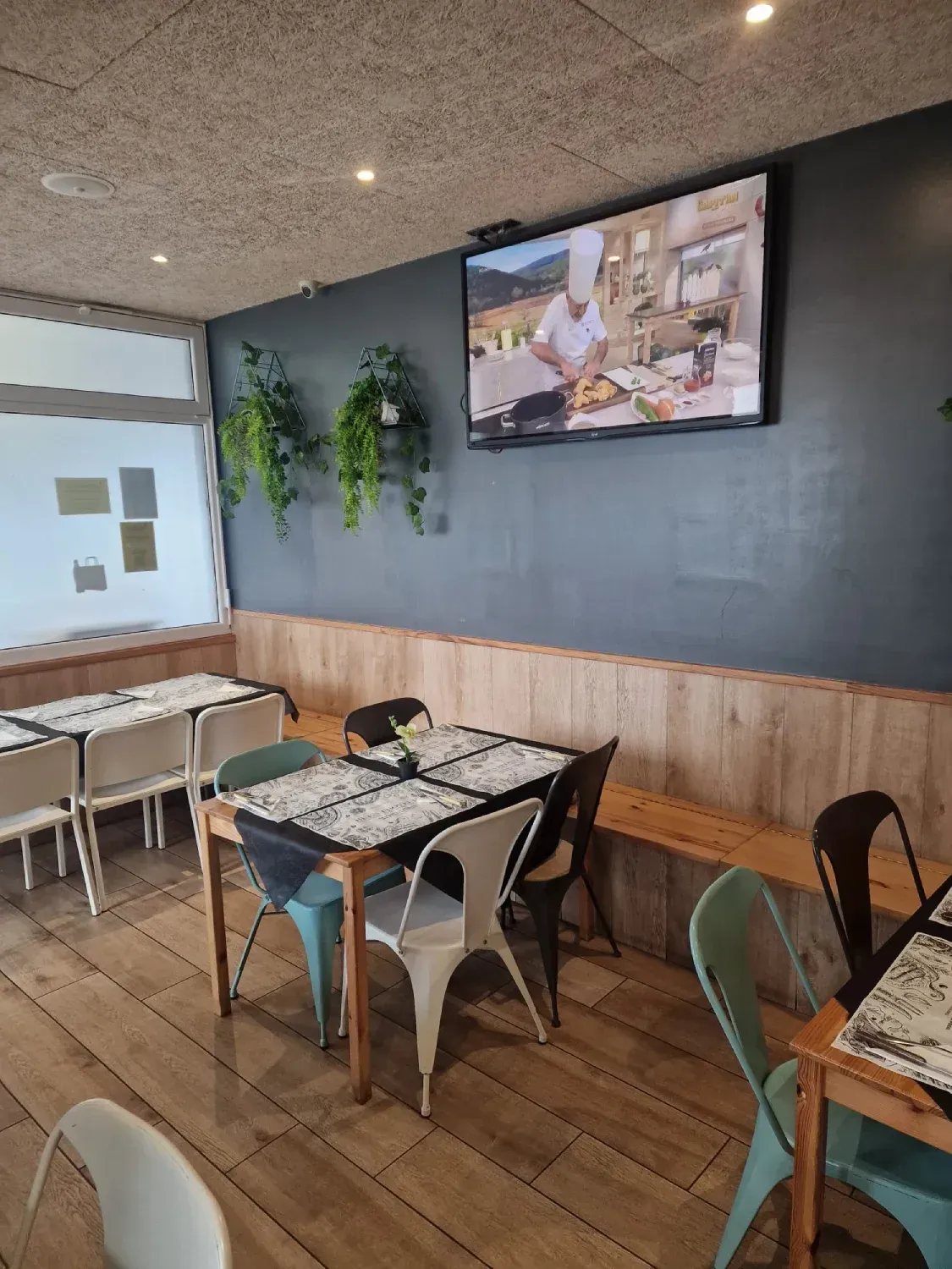 Un restaurante con mesas y sillas y un televisor en la pared.