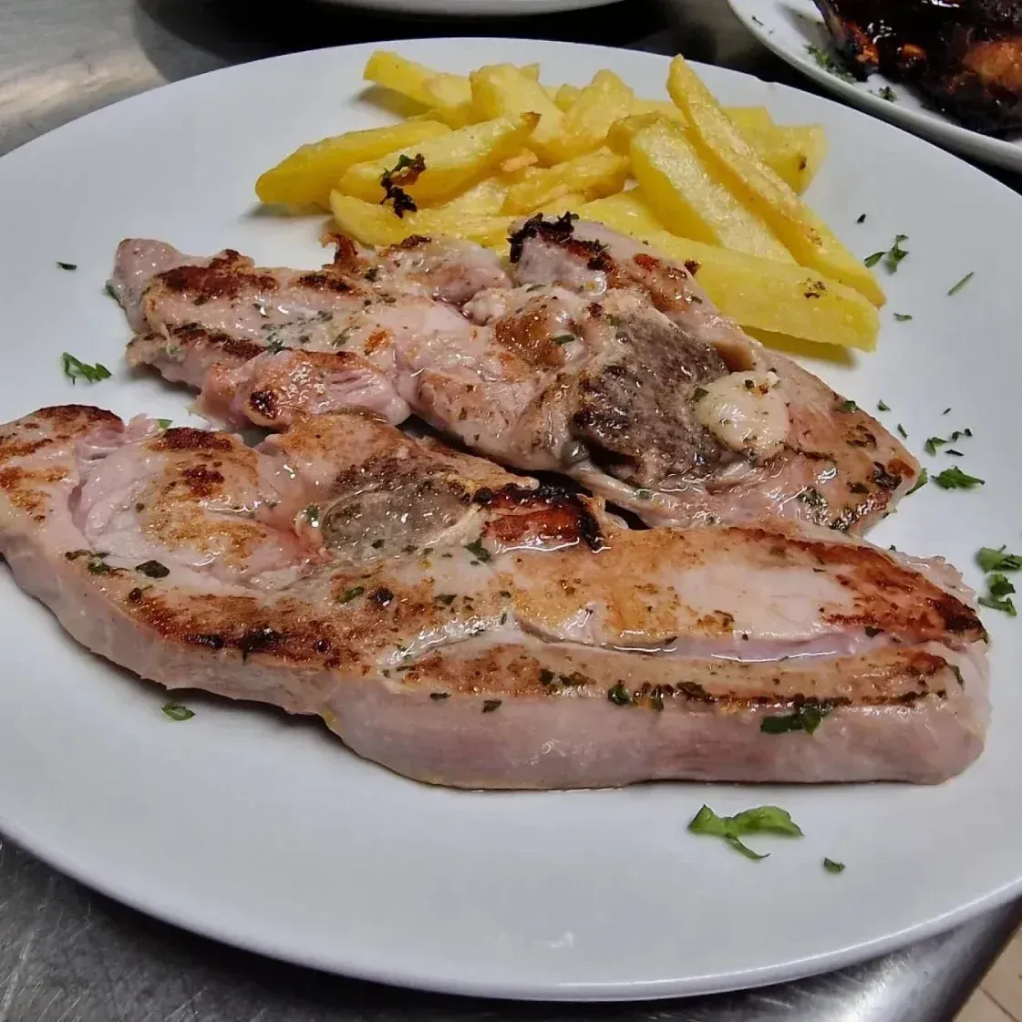 Un plato blanco cubierto con carne y papas fritas.