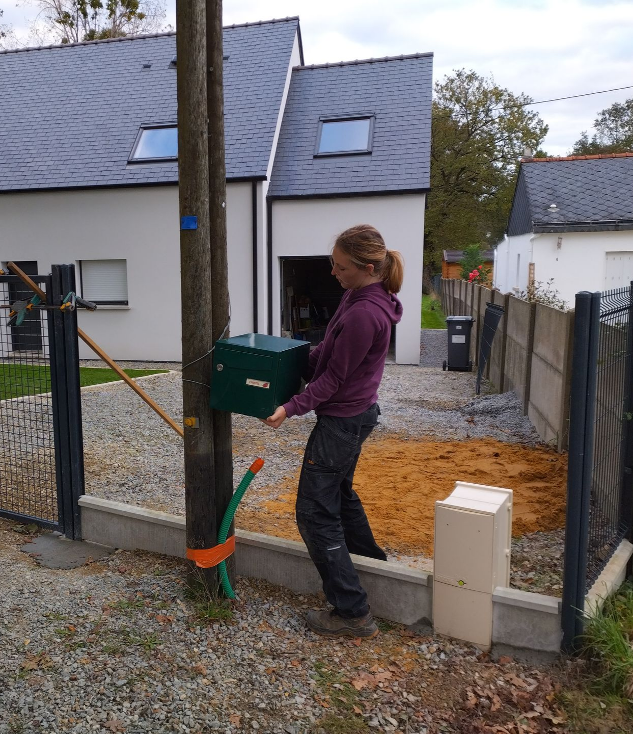 Une ouvrière pose une boite aux lettres