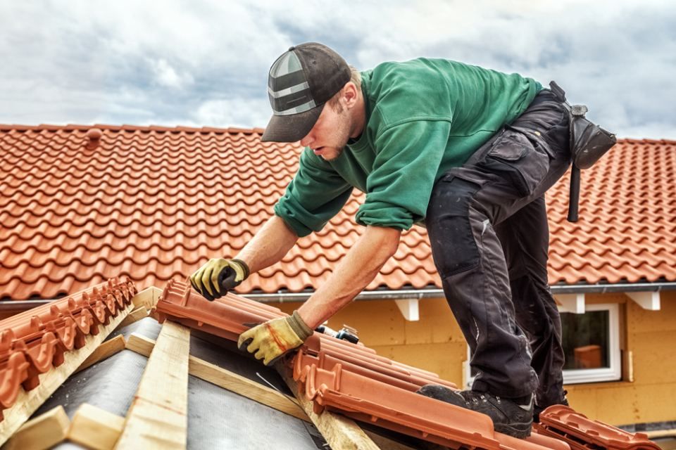 RW Dach GmbH & Co. KG – Dachdecker auf einer Dachspitze beim Installieren von Dachziegeln