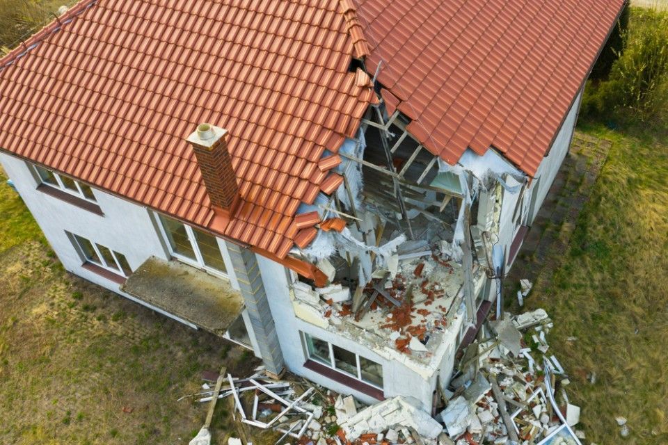 RW Dach GmbH & Co. KG – Sicht von oben auf ein Haus mit zerstörter Ecke, ein klaffendes Loch vom Dach bis in den ersten Stock
