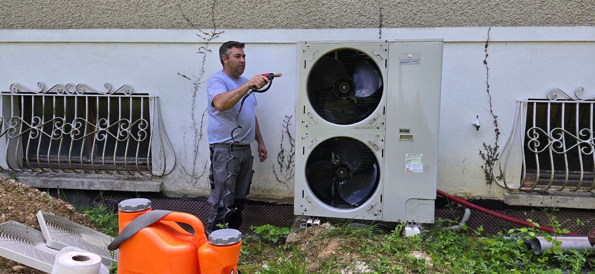 Un homme nettoie une climatisation à l'extérieur