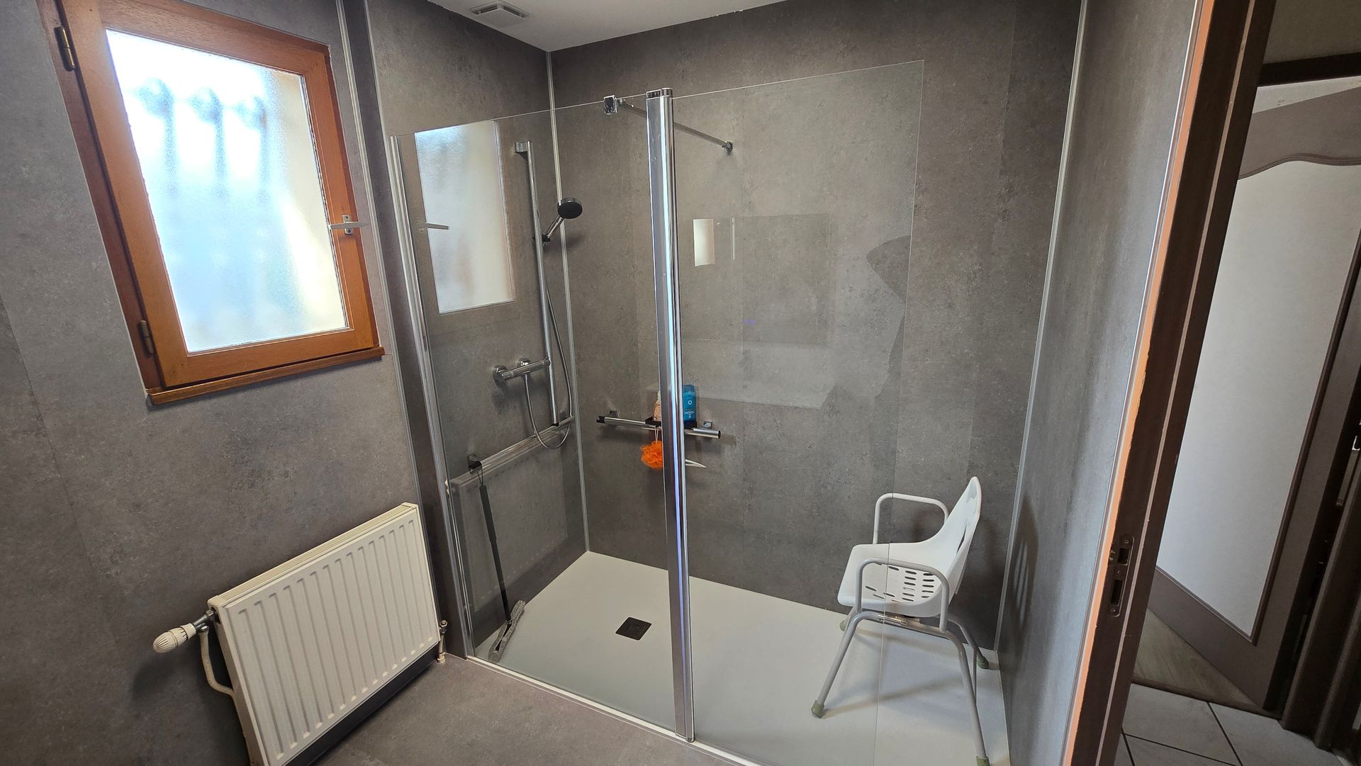 Une douche à l'italienne avec un siège dedans