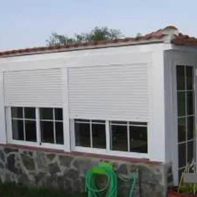 Una casa blanca con una manguera verde delante de ella.
