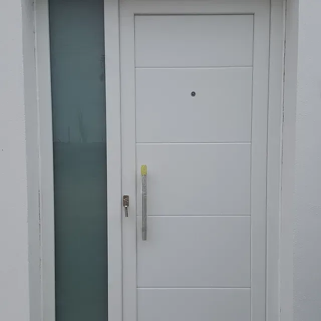 Una puerta blanca con una ventana de vidrio y un tirador en una pared blanca.