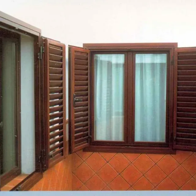 Una ventana con contraventanas de madera se abre a un suelo de baldosas.