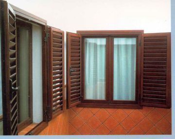 Una imagen de una ventana con contraventanas de madera sobre un suelo de baldosas.