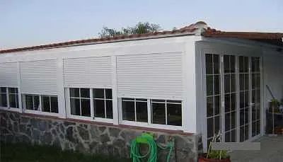 Una casa blanca con una manguera verde delante de ella.