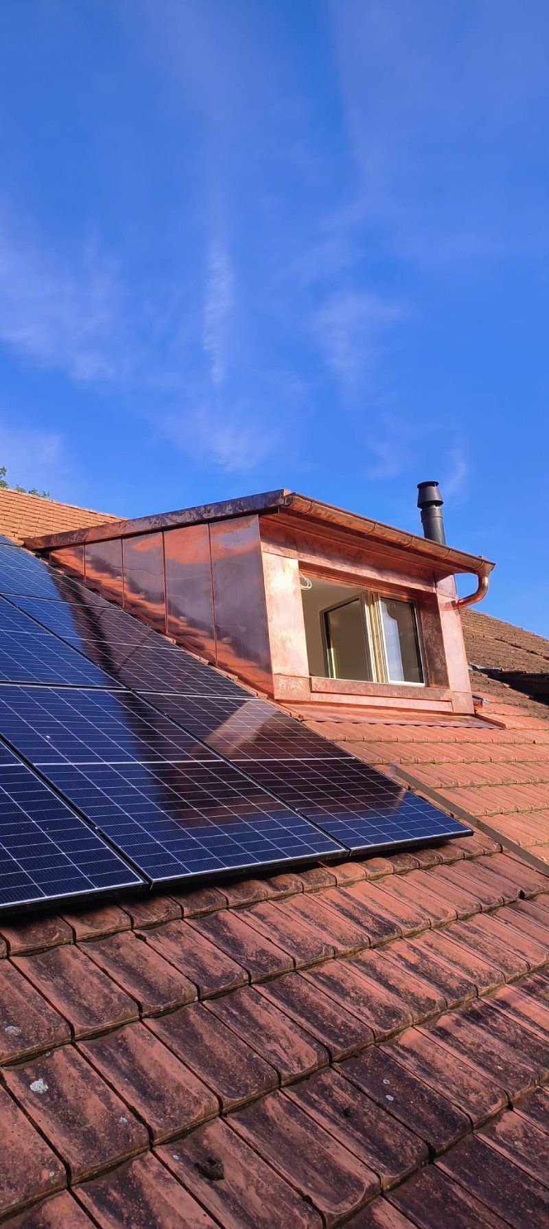 Un toit avec une fenêtre et des panneaux solaires dessus.
